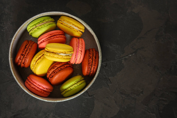 vista de cerca de macarrones coloridos sabrosos dulces sobre un fondo negro - Foto, Imagen