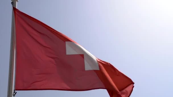 Sveitsin lippu lepattaa sinistä taivasta vasten hidastettuna - Materiaali, video