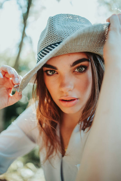 A vertical portrait of a young caucasian female with green eyes in a fedora hat - Foto, Imagen