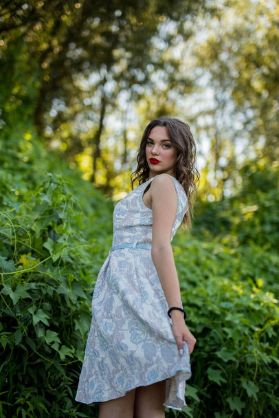A vertical shot of a young caucasian female in a light blue summer dress posing in nature - Zdjęcie, obraz