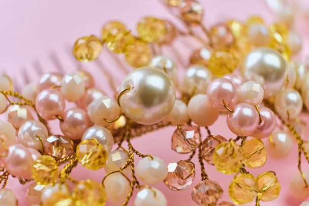 Gyönyörű haj dekoráció kézzel készített fésű fehér és sárga gyöngyök, közelkép, rózsaszín háttér. Gyöngyökből és gyöngyökből készült hajdísz. Szelektív fókusz - Fotó, kép