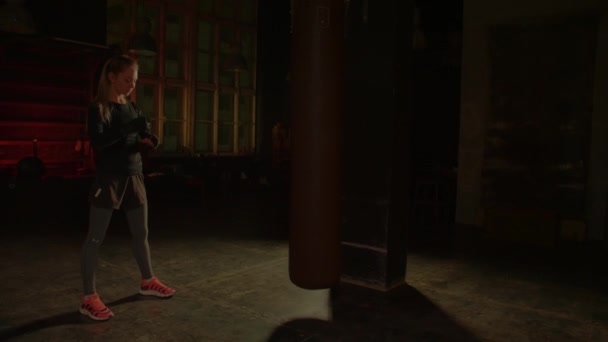 La luchadora se vendó las manos antes de entrenar en el gimnasio. Luz roja de neón - Metraje, vídeo