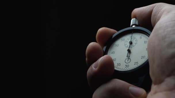 Black analogue stopwatch in hand on black background - Footage, Video