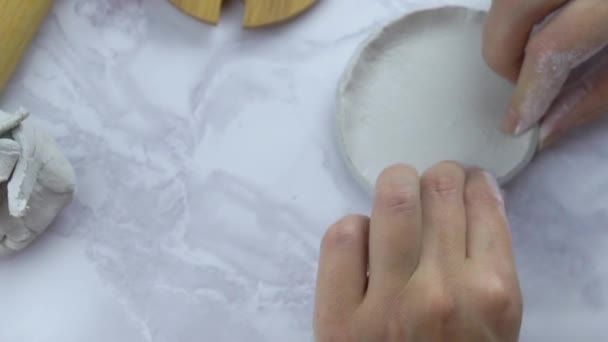 Person shapes circle of clay by bending edges. - Video, Çekim