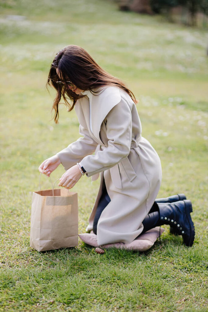щаслива молода жінка тримає ремісничу сумку присутня на відкритому повітрі в парку
 - Фото, зображення