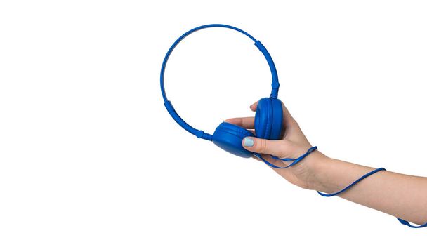 De hand van een meisje met een blauwe koptelefoon en een draad om haar arm. Apparatuur voor het luisteren naar muziek. - Foto, afbeelding