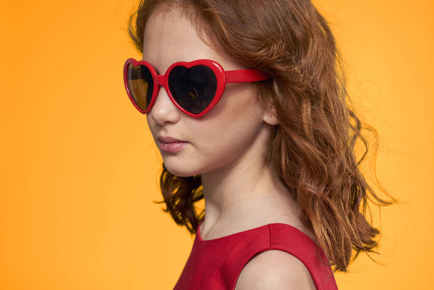 Girl in black glasses red dress childhood fun yellow background - Photo, image