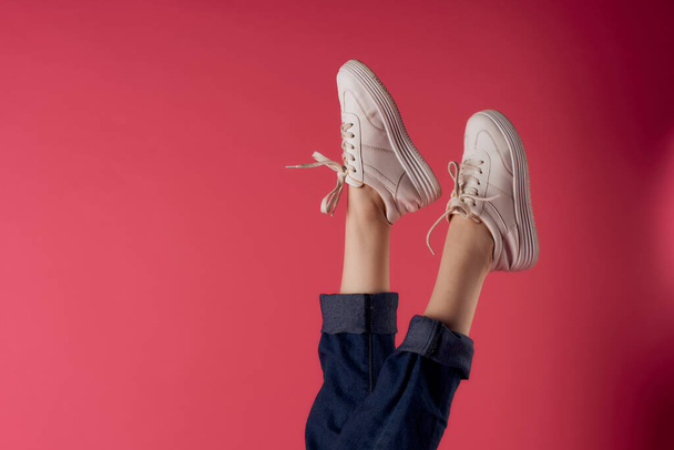 inverted female legs in white sneakers fashion studio pink background - Fotoğraf, Görsel