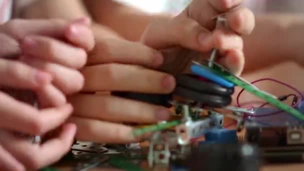 Marco wideo nastolatków ręce łączące różne szczegóły na drewnianym stole.  - Materiał filmowy, wideo