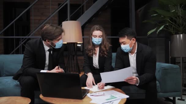 Uma equipe de empresários multinacionais em ternos e máscaras médicas decide cooperar internacionalmente no investimento no desenvolvimento de tecnologias de TI durante a pandemia da Covid19 na sala de reuniões. - Filmagem, Vídeo