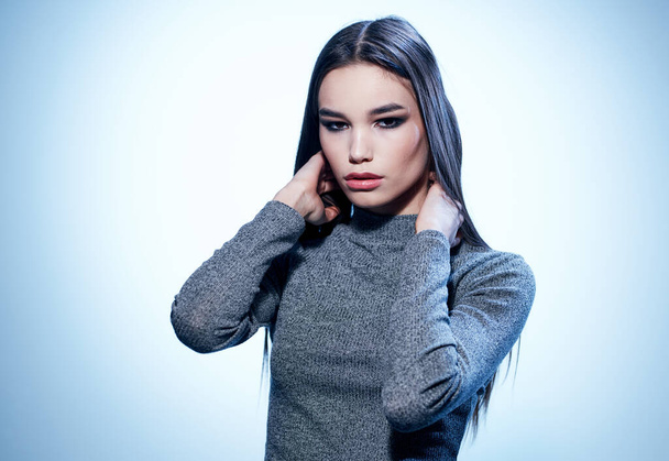 An elegant lady in a gray sweater gestures with her hands with makeup and eyeshadows - Photo, Image