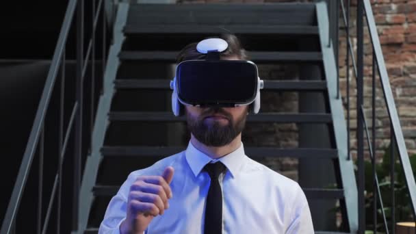 Ein Mann Büroleiter in offizieller Kleidung trägt Virtual-Reality-Brille und wischt im modernen Büro durch das Blättern von Online-Bildern. Augmented Reality Konzept. Mensch und Technik. - Filmmaterial, Video