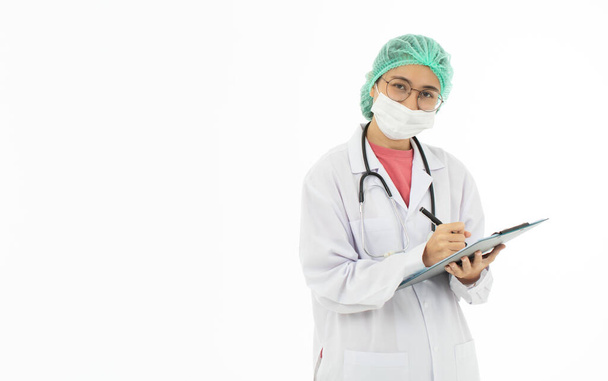 Portrait de médecin asiatique en robe blanche portant un masque d'hygiène protecteur écrit sur un dossier médical. Isolé sur fond blanc. - Photo, image