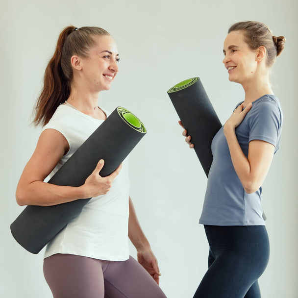 Dwie kobiety obracające maty do jogi po zajęciach ze szczęściem. - Zdjęcie, obraz