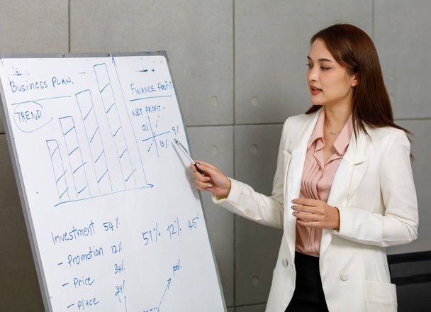 Businesswoman standing and explain about information on white board to meeting members - Photo, Image