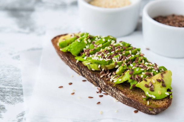 Healthy avocado toast on concrete background. Wholegrain bread, sesame flax seeds. Vegan keto diet. Healthy eating. Vegetarian Trendy guacamole sandwich. - Photo, Image