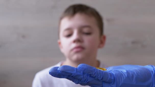 ラテックス・ニトリルの手袋をしている小児科医の医師は、子供に2つの丸薬を与えます。4K - 映像、動画