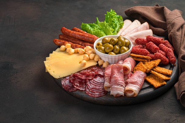Мясо и сыр деликатесы с травами и оливками на коричневом фоне. - Фото, изображение