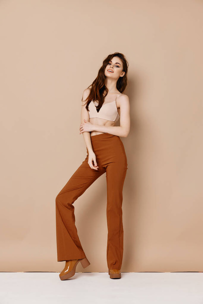 cute woman in trousers and in a t-shirt on a beige background high heel shoes model - Photo, Image