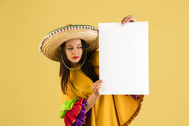 Young beautiful happy girl in sombrero isolated over yellow background. - Photo, Image