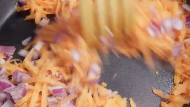 Cipolle fritte e carote in una pentola. Verdure arrosto, ingredienti di cottura. - Filmati, video