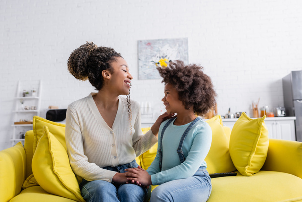 iloinen afrikkalainen amerikkalainen äiti ja lapsi katselee toisiaan puhuessaan sohvalla kotona - Valokuva, kuva