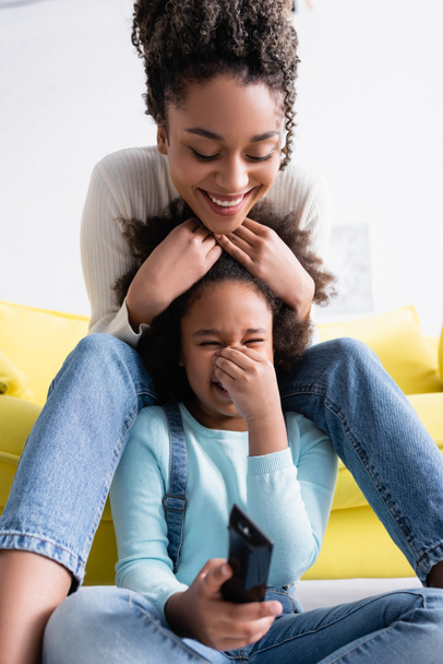 joyful african american woman touching head of laughing daughter watching comedy film - Photo, Image