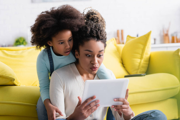 surprised african american girl with mom looking at digital tablet - Photo, Image