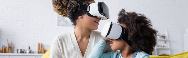 изумленный африканский американец ребенок и улыбающаяся мать игры в VR гарнитуры дома, баннер - Фото, изображение