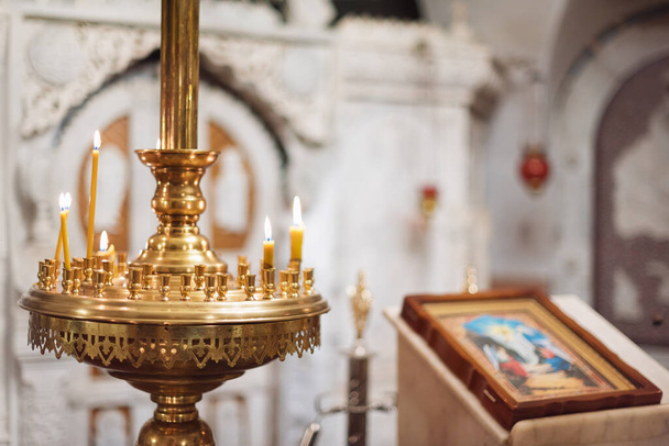 Orthodox christelijke kerk interieur. Ikoon en kaarsen tijdens de eredienst - Foto, afbeelding