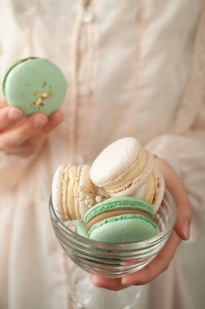 Macarons in de hand van een mooi meisje in pastel lichte kleur - Foto, afbeelding