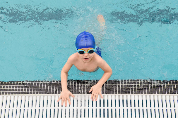 vue de dessus d'un garçon de 7 ans jouant et nageant dans la piscine - Photo, image