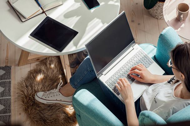Νεαρή γυναίκα που χρησιμοποιεί φορητό υπολογιστή για να εργαστεί στο σπίτι, απομακρυσμένη εργασία - Φωτογραφία, εικόνα