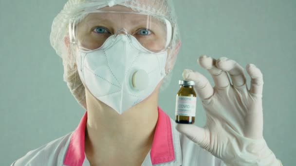 顔保護マスクの医学研究者は、細菌学的研究室で抗コロナウイルスモデナワクチンとアンプルまたはボトルを保持 - 映像、動画