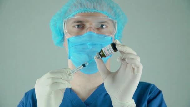 Mies lääkäri suojaava naamio käsineet ja lasit valitsee anti-coronavirus rokote ruiskuun pullosta hoitolaitoksen - Materiaali, video