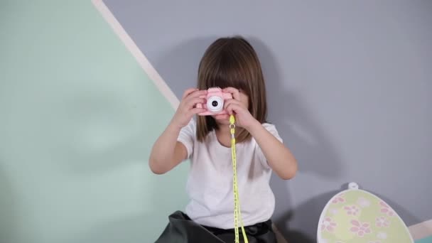 Młoda fotograf dziewczyna zrobić zdjęcie jej aparat zabawka. Cute little girl grać w domu - Materiał filmowy, wideo