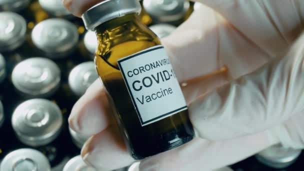 Mano viróloga en guantes protectores con potencial vacuna anti coronavirus en frasco o frasco estéril con medicamentos de farmacia - Metraje, vídeo