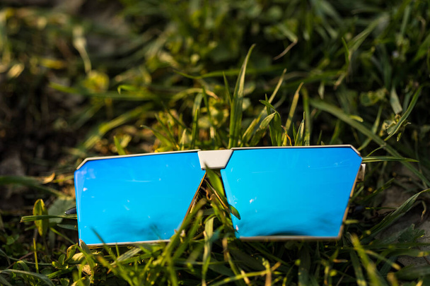 Zróżnicowany model okularów przeciwsłonecznych z niebieskimi soczewkami kręci się na zewnątrz w letni dzień zbliżenia. Skupienie selektywne - Zdjęcie, obraz