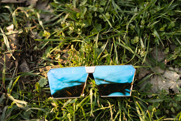 Modèle de lunettes de soleil surdimensionnées avec des lentilles bleues tournent à l'extérieur dans un gros plan de jour de consommation. Concentration sélective - Photo, image