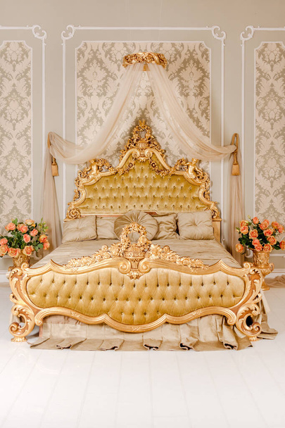 Chambre de luxe dans des couleurs claires avec des détails de meubles dorés. Grand lit double royal confortable dans un élégant intérieur classique. - Photo, image