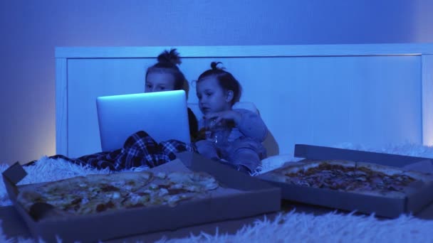 Deux petits garçons couchés au lit, regardent un film sur ordinateur portable et mangent de la pizza la nuit - Séquence, vidéo