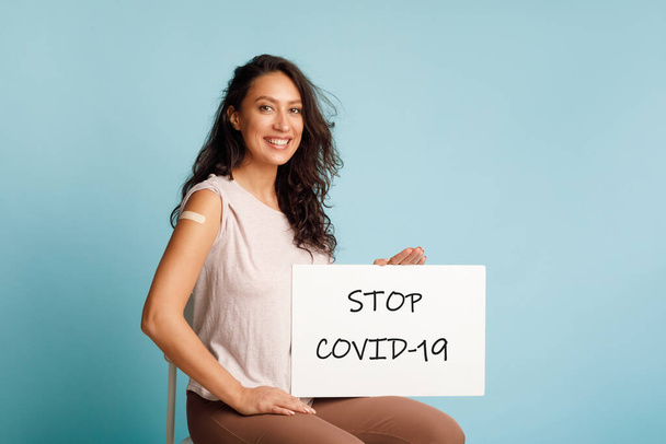 Εμβολιασμένο κυρία Εμφάνιση Αφίσα Stop Covid-19 Διαφημιστικός Εμβολιασμός, Μπλε Φόντο - Φωτογραφία, εικόνα