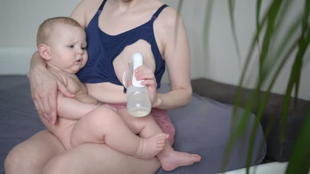 Jeune mère avec nouveau-né mignon bébé garçon nu, le tenant sur les bras, en utilisant le tire-lait étreignant et allaitant avec du lait maternel. Enfant en santé, concept d'hôpital et de maternité heureuse. Pépinière. - Séquence, vidéo
