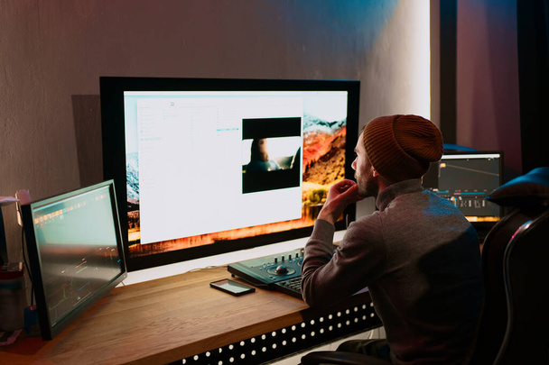 Editor de vídeo masculino trabalhando em seu computador pessoal com grande exibição - Foto, Imagem