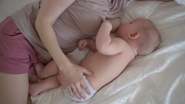 Nuori äiti makaa vastasyntyneen söpö pikkulapsi alaston vauva poika sängyssä, pitämällä häntä aseita, halaus ja imettää rintamaidolla. Terve lapsi, sairaalan käsite ja onnellinen äitiys. Lastenhuone - Materiaali, video