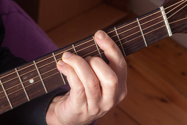 Крупный план на руке человека, играющего на гитаре - Фото, изображение