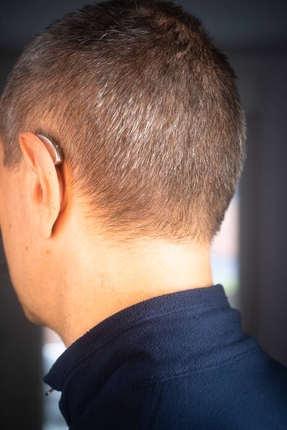 Nowoczesny cyfrowy aparat słuchowy w uchu mężczyzny w wieku 40 lat - Zdjęcie, obraz