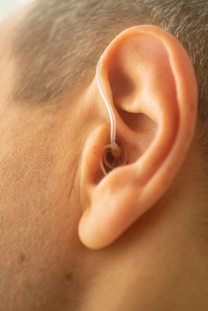 Apparecchio acustico digitale moderno nell'orecchio dell'uomo di mezza età degli anni '50 - Foto, immagini