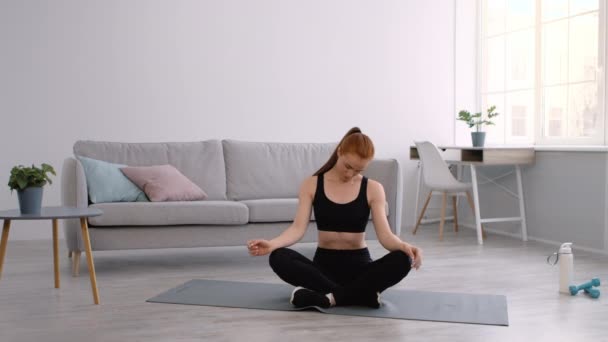 Γυμναστική γυναίκα κάνει το λαιμό άσκηση περιστρεφόμενο κεφάλι κάθεται στο σπίτι - Πλάνα, βίντεο