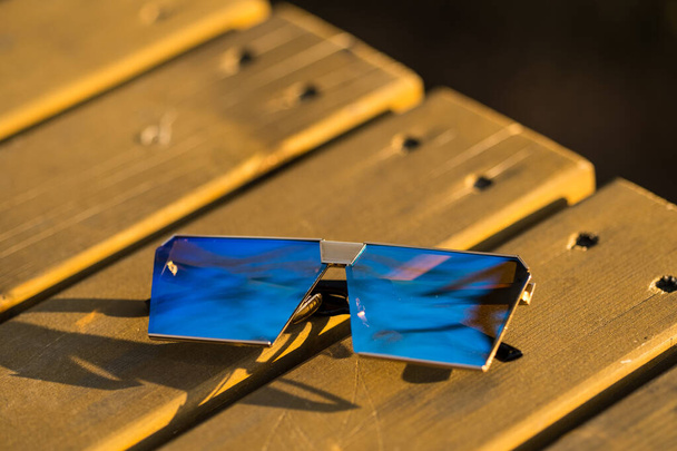 Güneşli bir günde mavi lensli büyük güneş gözlüğü modeli dışarıda çekim yapıyor. Seçici odak - Fotoğraf, Görsel